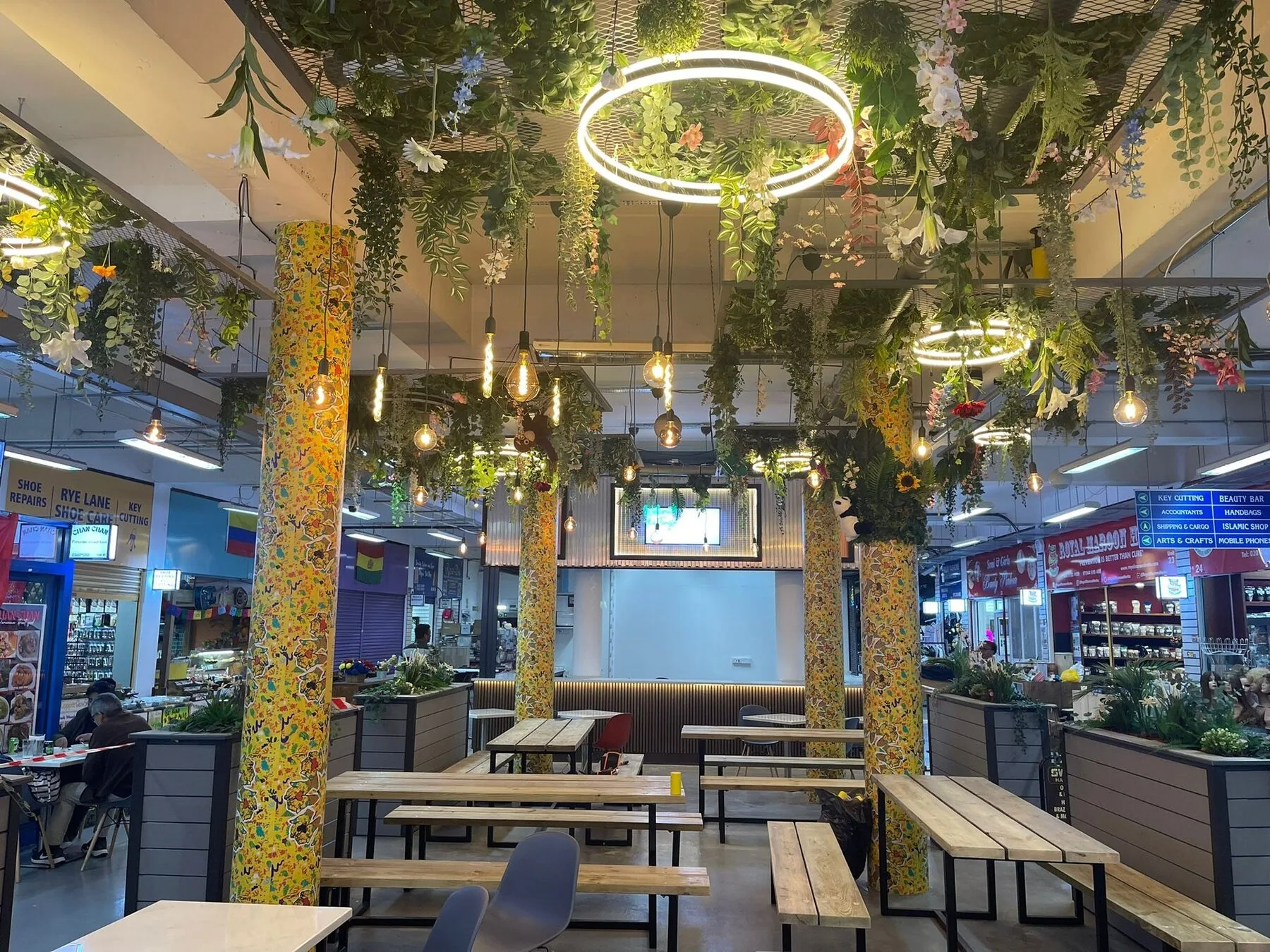 The food hall at Rye Lane Market with signs for key cutting, beauty bar, accountants and more