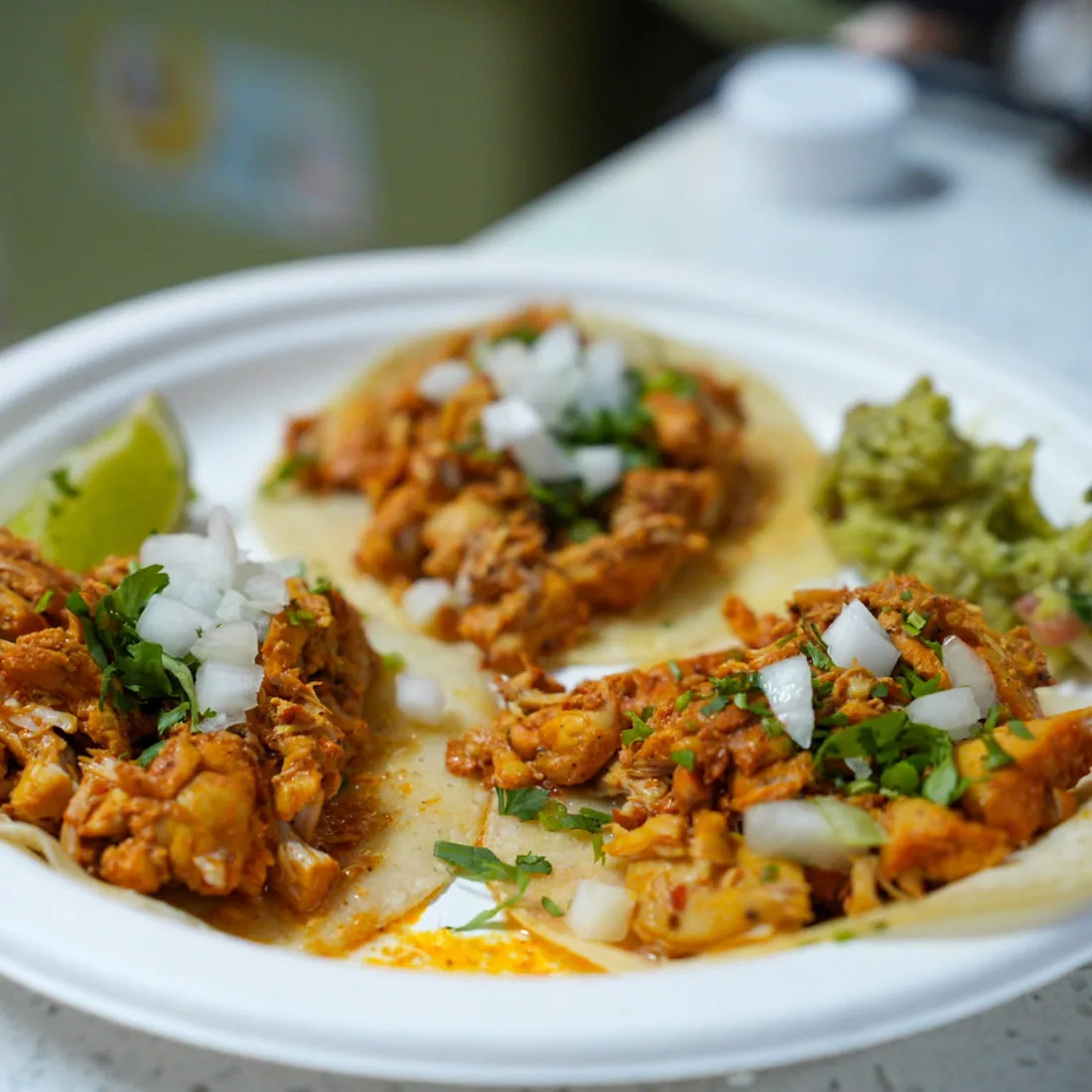 A plate of tacos al pastor with lime and guacamole