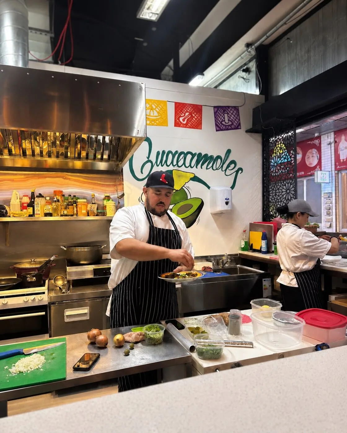 The chef plating up at Guacamoles, beneath the wall mural